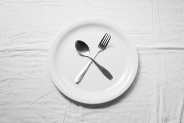 Spoon and fork on white plate on white background