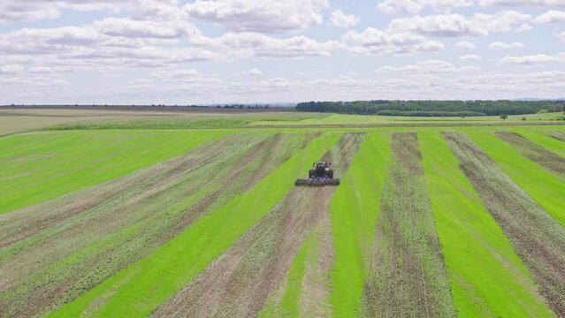 Machines till the fields for the coming harvest year. Wide angle drone shot.