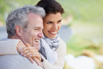 Fototapeta premium Couple, face and laughing in nature with hug for romance, love and relationship outdoor with date. Mature, man and woman or embrace with happy, marriage and trust for bonding, honeymoon and support