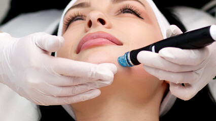 Professional dermatologist in medical gloves doing hydro peeling procedure for beautiful woman...
