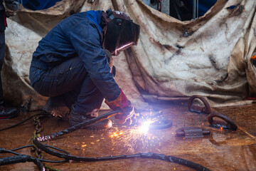 A welder cuts steel fasteners on the deck with a plasma cutter. - obrazy, fototapety, plakaty