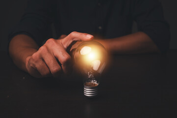 Idea concept. Hand of man holding illuminated light bulb, concept creativity with bulbs that shine glitter. Inspiration of ideas for sustainable business development.