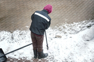 Worker breaking ice with hand ice chopper. Worker remove ice and snow with icebreaker from snowy...