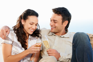 Couple, drinking champagne and toast for honeymoon and good news for celebration, announcement and love. Looking at wife, smile and happy with romantic gesture, bonding together and anniversary