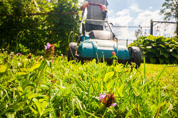 Lawn mover on green grass in modern garden or backyard. Machine for cutting lawns. Gardening care tools and equipment. Process of lawn trimming