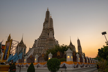 Fototapeta premium scenery sunset behind the large illuminated temple Wat Arun the biggest and tallest pagoda in the world beside Chaophraya river Bangkok, Thailand..pagoda in golden sunset popular landmark in Bangkok