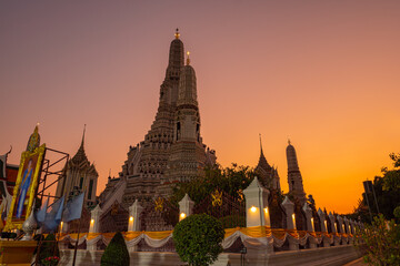 Fototapeta premium scenery sunset behind the large illuminated temple Wat Arun the biggest and tallest pagoda in the world beside Chaophraya river Bangkok, Thailand..pagoda in golden sunset popular landmark in Bangkok