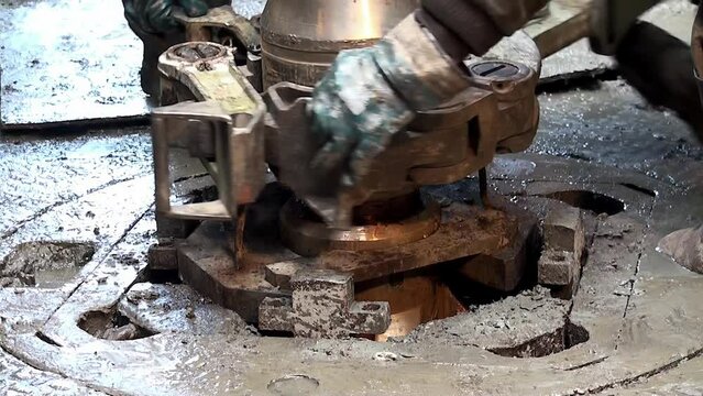 Installing a new drilling bit at the wellhead of the oil derrick.
