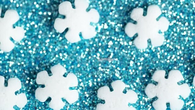 Sweet sugar sprinkles on blue glitter background, macro video. Sprinkles of white sugars snowflakes, rotation.