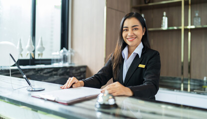 Beautiful asian hotel receptionist in  uniforms at desk in lobby Friendly and welcome staff in hotel reception counter. - obrazy, fototapety, plakaty