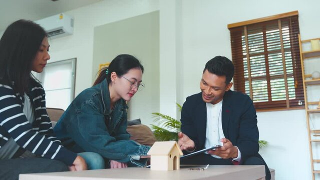 realtor bringing real estate insurance contract for young couple to sign documents at home