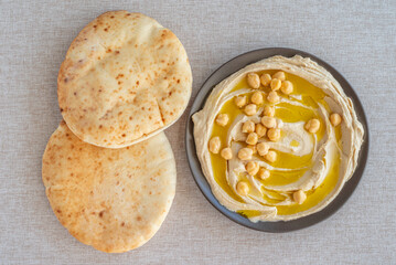 Hummus plate and flatbread on cotton fabric background.
