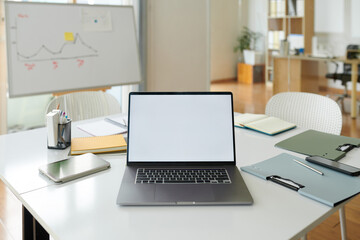 Laptop with empty screen on desk in boardroom