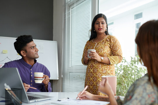 Indian business colleagues in traditional clothes having coffee and discussing news and gossips