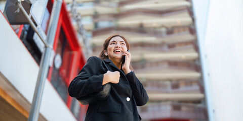 Fototapeta premium Business woman successful using smartphone walking outdoors to work. beautiful woman going to working with smartphone walking near office building