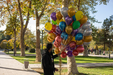 the man selling lot of colorful balloons in the street
