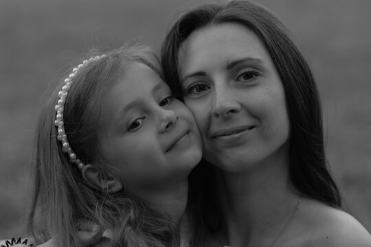Contented smiles on a child and adult's faces in a tranquil embrace, captured in a natural setting. The photo reflects the importance of mental wellness and family support. - Powered by Adobe