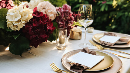 Fototapeta premium Wedding or formal dinner holiday celebration tablescape with hydrangea flowers in the English countryside garden, table setting and wine, floral table decor for family dinner party, home styling