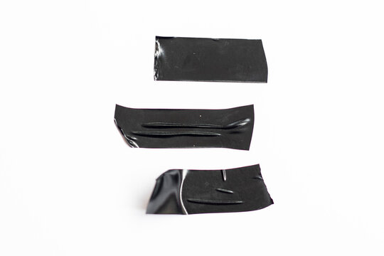 Piece of torn black ribbon isolated on white background. A set of crushed plastic adhesive tape