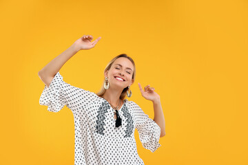 Portrait of smiling hippie woman dancing on yellow background