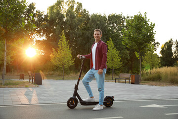 Happy man with modern electric kick scooter in park