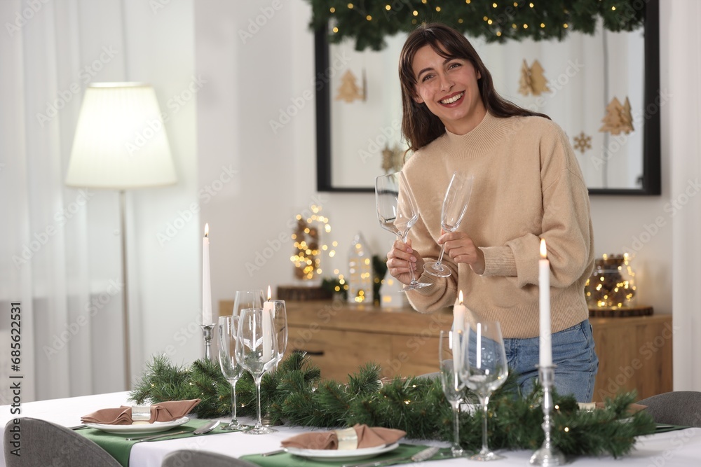 Wall mural Smiling woman setting table for Christmas celebration at home. Space for text