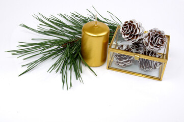 Christmas decorations with candle pine twigs and cones covered with snow in golden tone