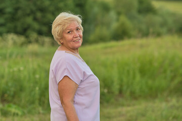 Fototapeta na wymiar The gentle smile of a mature woman outdoors at sunset. Highlights the growing focus on nature's role in enhancing quality of life for the aged.