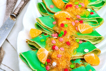 Christmas pancakes with mandarin sauce and sweet sprinkles. Festive New Year dessert, ready to eat