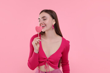 Pink look. Beautiful woman with lollipop on color background