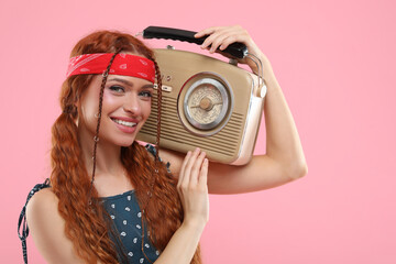 Stylish young hippie woman with retro radio receiver on pink background