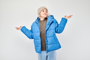 Young woman in blue winter jacket holding something in hand, demonstrating empty space for product...