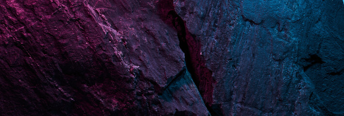 Black stone texture in pink blue neon lighting, dark abstract background. Natural mineral rock close up details, empty backdrop with copy space for design