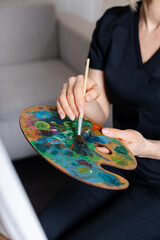 the artist paints in the studio. holding a palette of paints in his hand, drawing recognizable...