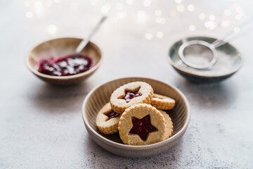 Kekse mit Erdbeerkonfitüre in einer Schüssel und Zuaten auf einem grauen Tisch. Nahaufnahme, Weihnachten.