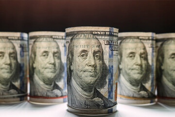 Close-up of a hundred dollar bill in the foreground with other American bills blurred in the background.