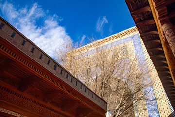 blue sky with a beautiful wooden roofs in historical building, Khiva, the Khoresm agricultural...