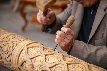 man crafting a wooden beam with his hand in Old traditional way, old traditional handcraft, Khiva,...