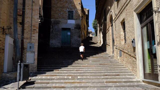 Child runs down the steps of the village of Corinaldo. Italy, Marche region.