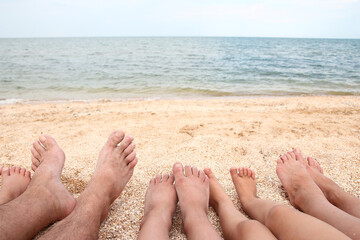 A Legs of the beautiful whole family on the sand near the sea background