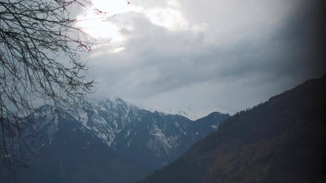 4K shot of dark clouds above the snow covered Himalayan mountains during the winter season at Manali in Himachal Pradesh, India. Dark clouds cover the mountain peak during incoming snow storm.
