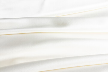 Elegant satin fabric with a creamy color. The luxurious texture of the soft folds of the fabric....