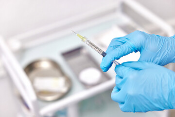 Physician hand in blue gloves with syringe for injection