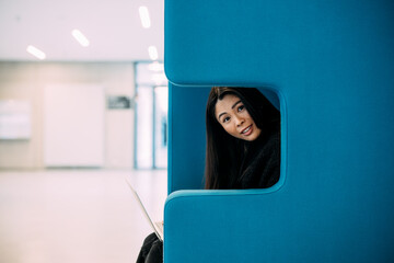 Beautiful businesswoman sitting with laptop on blue chair at workplace