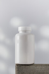  Mockup is a white jar with pills or vitamins on a podium. Medical preparations.