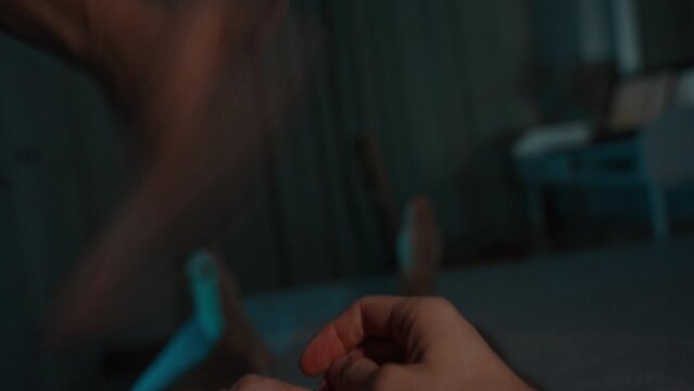 Concept of Video Game Addiction. Woman takes the phone from the man and scolds him. Dark room, POV on the bed. Chroma Key Layout on the Smartphone.