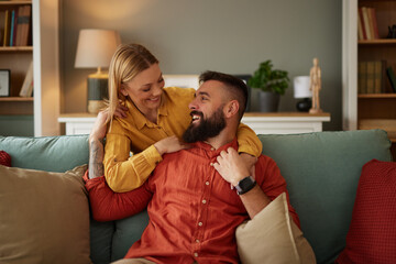 Smiling couple hugging on sofa in living room