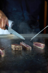 Professional chef cooking delicious juicy beef steak on restaurant stove, selective focus