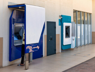 african american young person using an ATM machine in a shopping complex