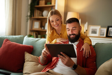 Handsome couple relaxing at home and looking at tablet